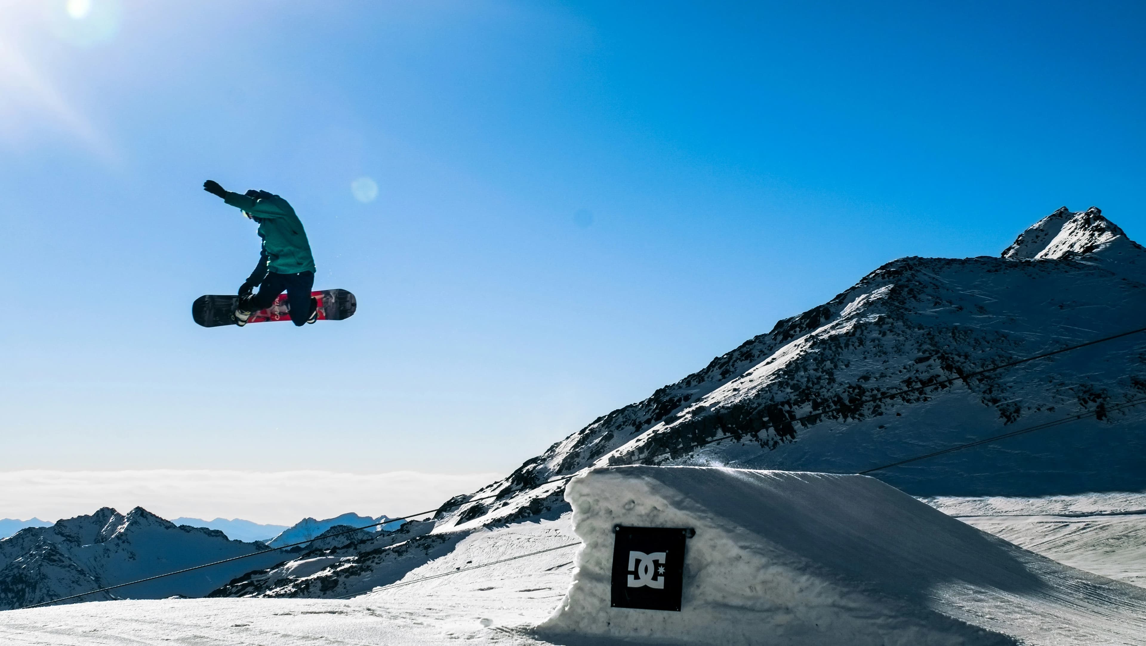 Snowboarder getting big air in front of a mountain skyline